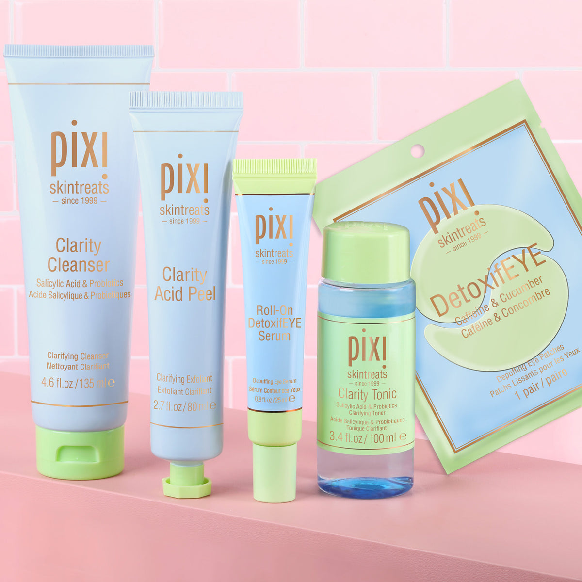 Clear Skin Reset Bundle shown on a pink background featuring Clarity Cleanser, Clarity Acid Peel, Clarity Tonic, Roll-On DetoxifEYE Serum and DetoxifEYE pair of patches -